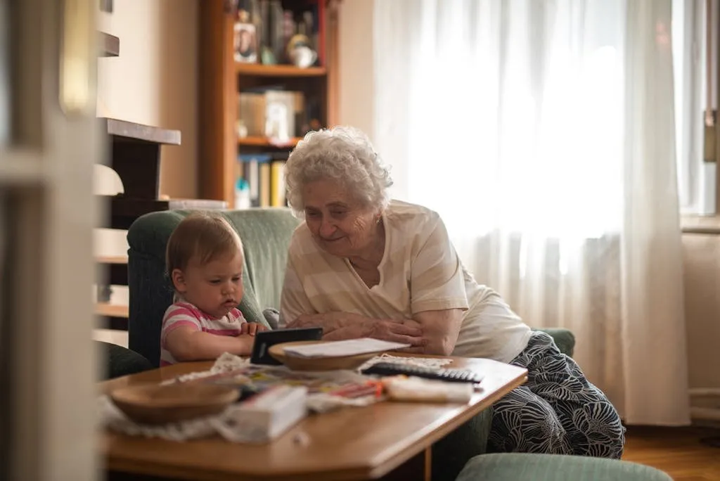 Elderly woman and baby enjoying together time indoors.