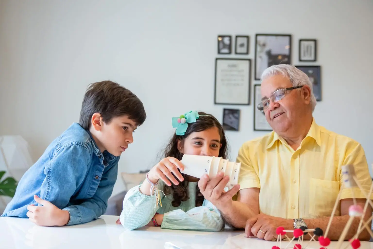 Grandfather enjoying a playful moment with his grandchildren indoors, fostering bonding and learning.